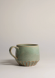 Green ceramic mug on a light gray background
