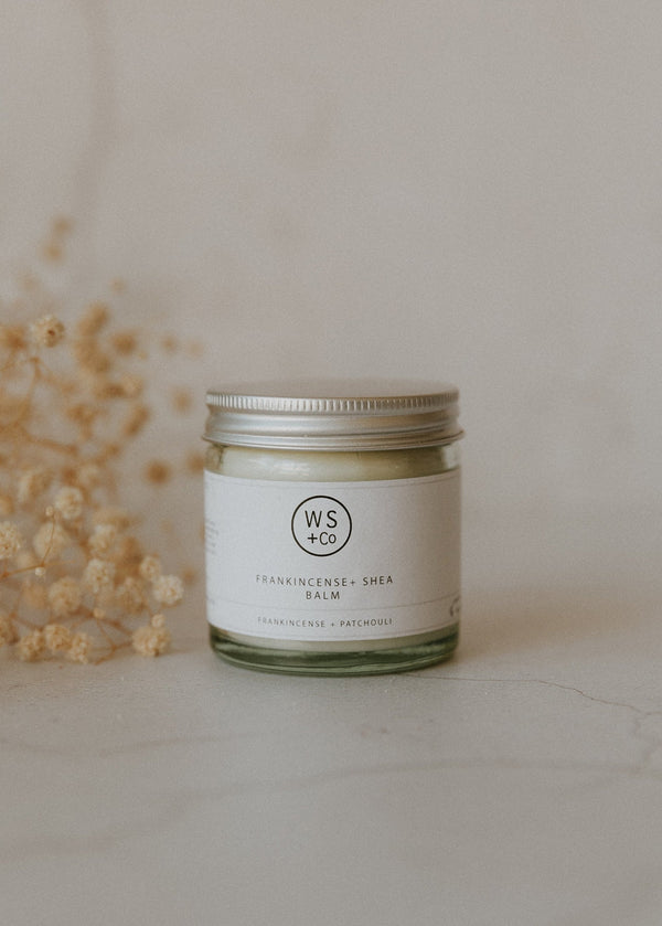 Jar of balm with a label on a light surface with dried flowers.