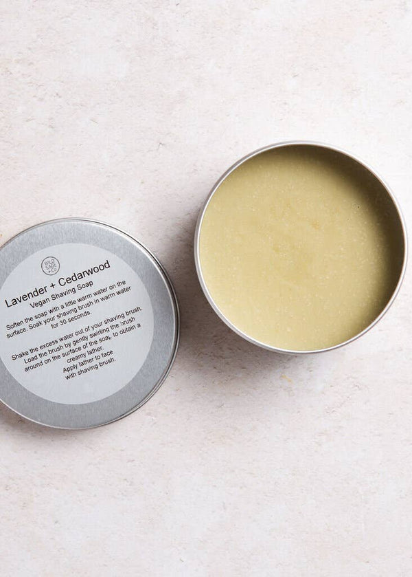 Open tin of lavender and cedarwood shaving soap on a light background