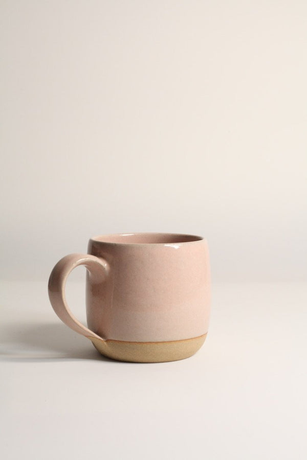 A beige ceramic mug with a handle, placed against a plain background.