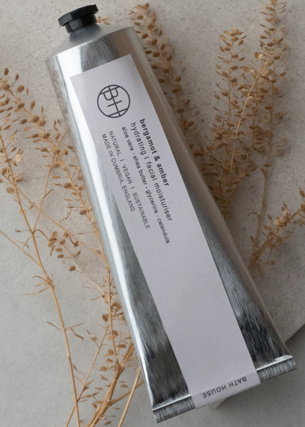 Tall silver tube with black cap on a neutral background with dried plants