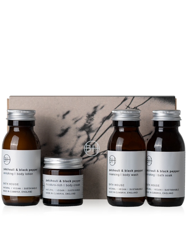 Set of four skincare products with labels in front of a decorative box on a white background