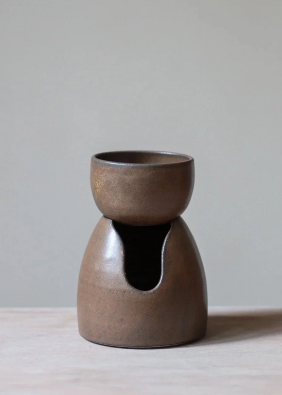 Brown ceramic oil burner on a light surface with a neutral background