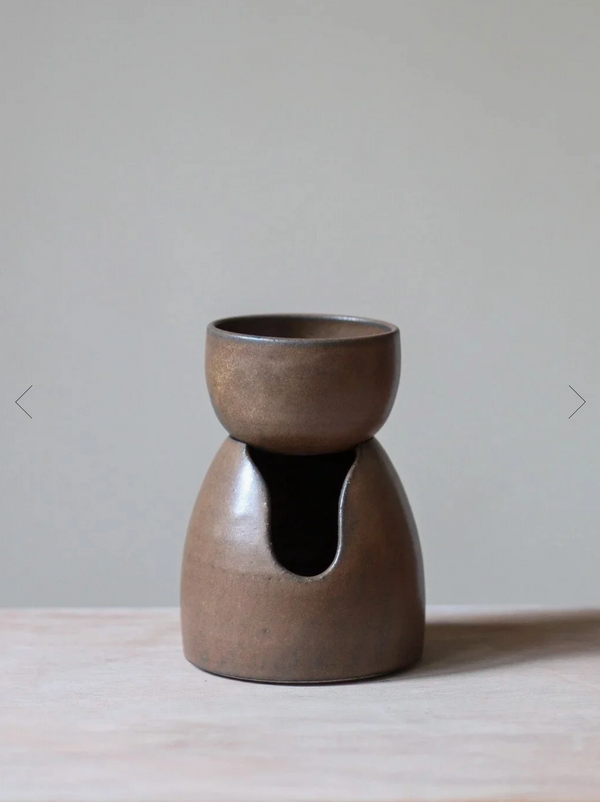 Brown ceramic oil burner on a light surface with a neutral background