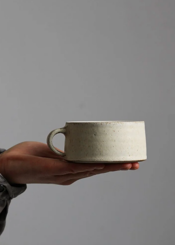 Hand holding a ceramic mug against a plain background