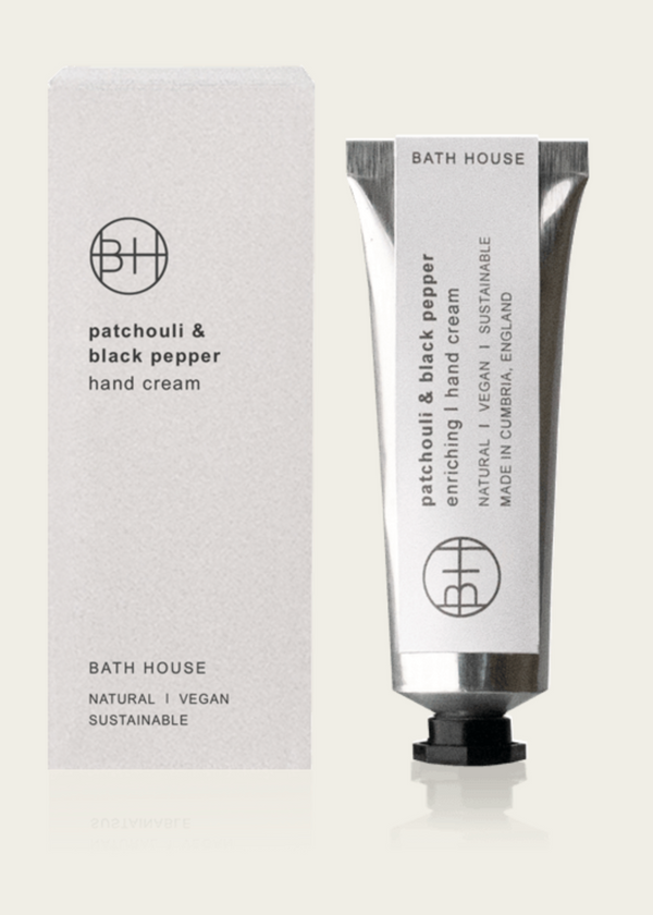 A tube of Bath House Patchouli & Black Pepper Hand Cream with its packaging, both featuring a minimalist design with black and white colors.