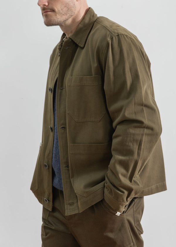 Man wearing a brown jacket and pants with a gray knit cap on a white background