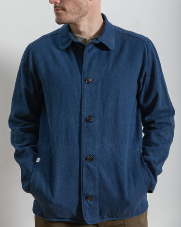 Man wearing a blue jacket with buttons on a plain background