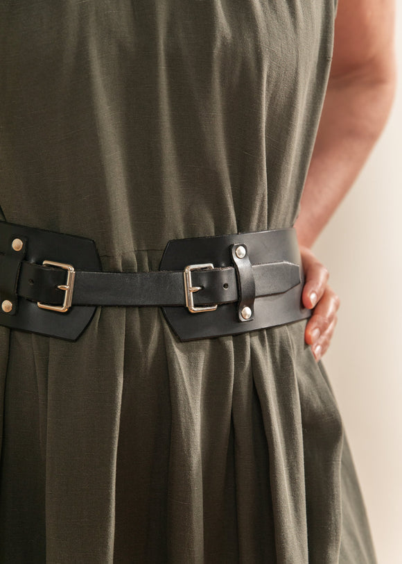 Green dress with a black belt featuring gold buckles on a neutral background