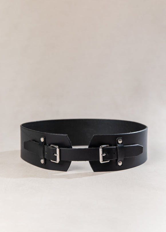 Black leather belt with metal buckles on a light beige background