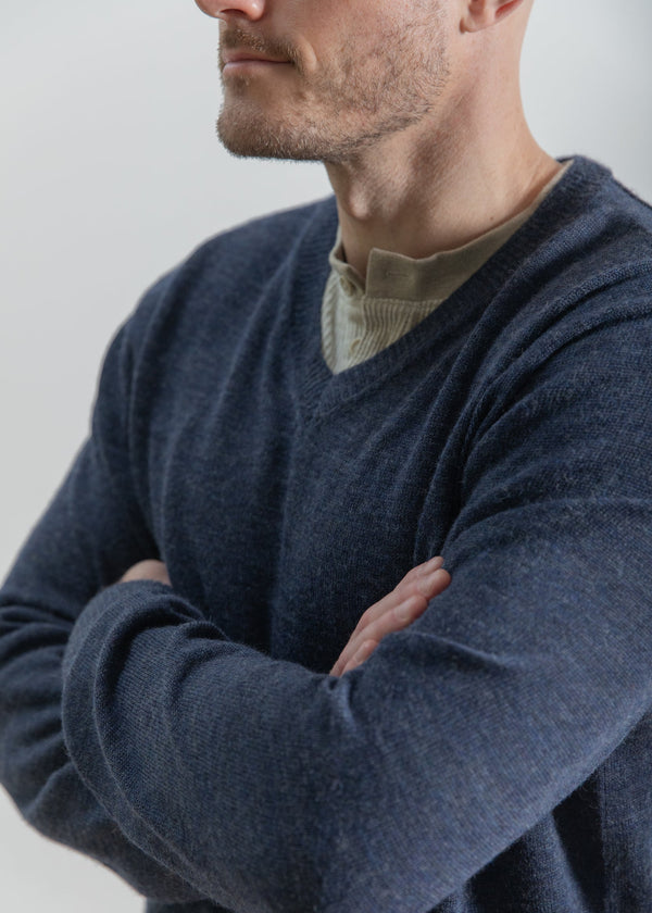 Man wearing a dark blue sweater with a plain background