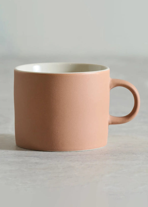 Pink mug on a light gray surface with a neutral background