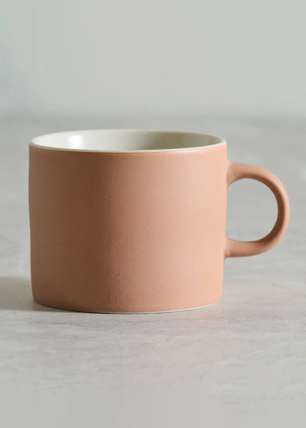Pink mug on a light gray surface with a neutral background