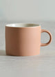 Pink mug on a light gray surface with a neutral background