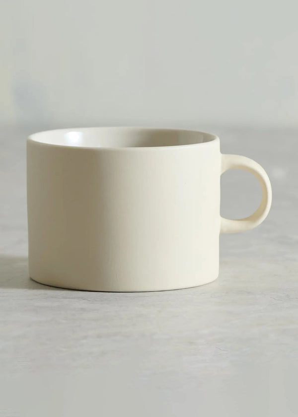 White ceramic mug on a light gray surface with a neutral background