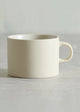 White ceramic mug on a light gray surface with a neutral background