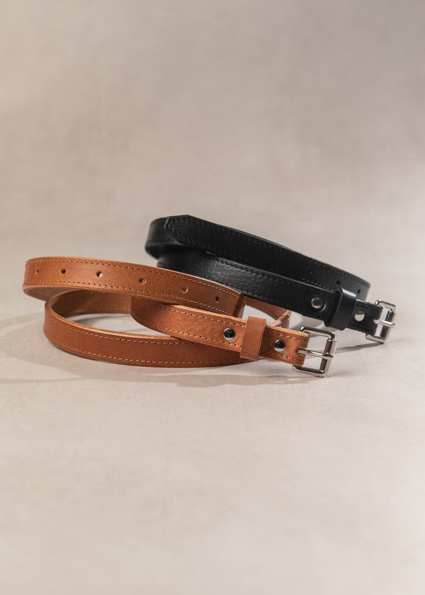 Two leather belts, one brown and one black, on a beige background.