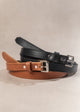 Two leather dog collars, one black and one brown, on a beige background.