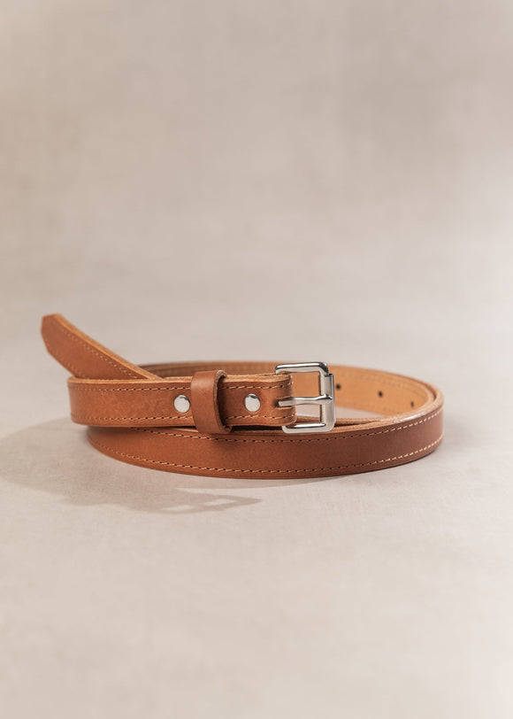 Brown leather belt with a silver buckle on a beige background