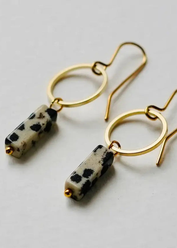 Gold hoop earrings with black and white bead drops on a light gray background