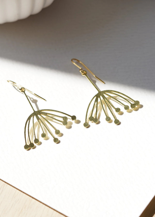 Gold earrings on a light surface with soft shadows