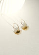 Gold earrings on a white textured surface