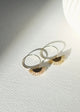 Gold hoop earrings with sunburst designs on a textured white surface