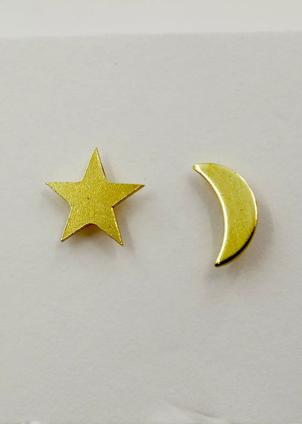 Gold star and moon earrings on a light gray background