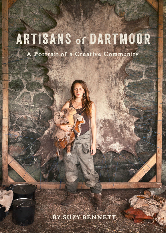 Book cover of 'Artisans of Dartmoor' with a person holding a sheepskin against a stone wall.