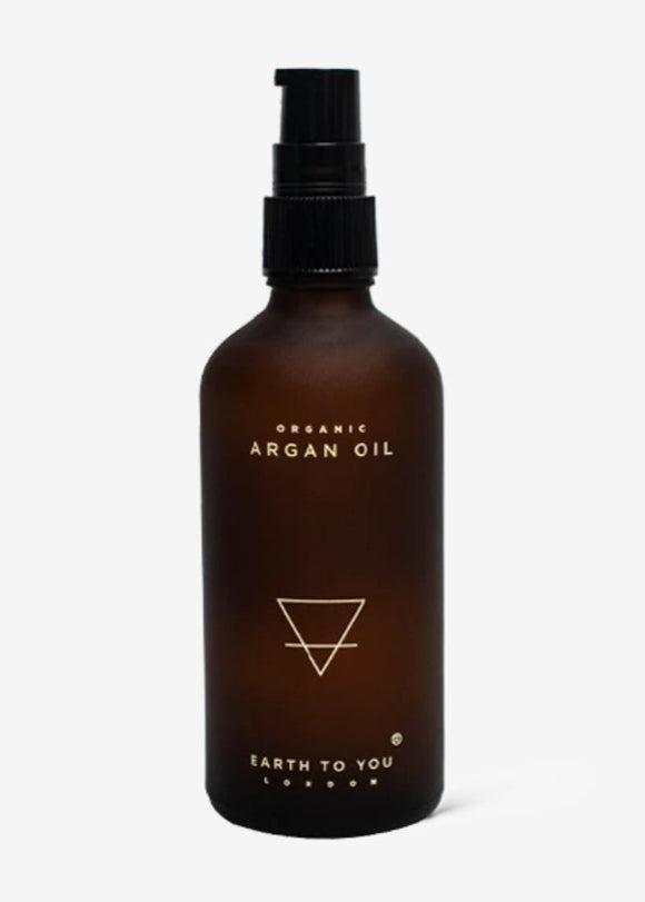 A brown glass bottle with a black pump dispenser labeled 'Organic Argan Oil' by Earth to You.
