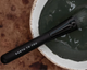 Black makeup brush with 'Earth to You' branding on a textured surface.