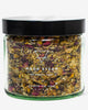 A clear glass jar containing a blend of dried herbs and flowers labeled as 'Moon Steam' for skincare purposes.