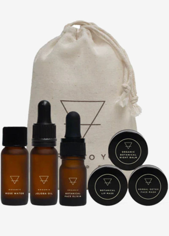 A collection of bath and body products including bottles and pots, arranged in front of a beige cotton drawstring bag with a graphic logo.