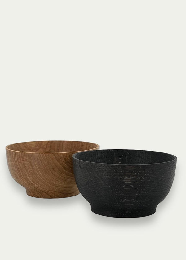 Two wooden bowls, one brown and one black, on a white background