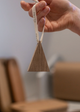Hand holding a wooden triangle xmas decoration with a blurred indoor background