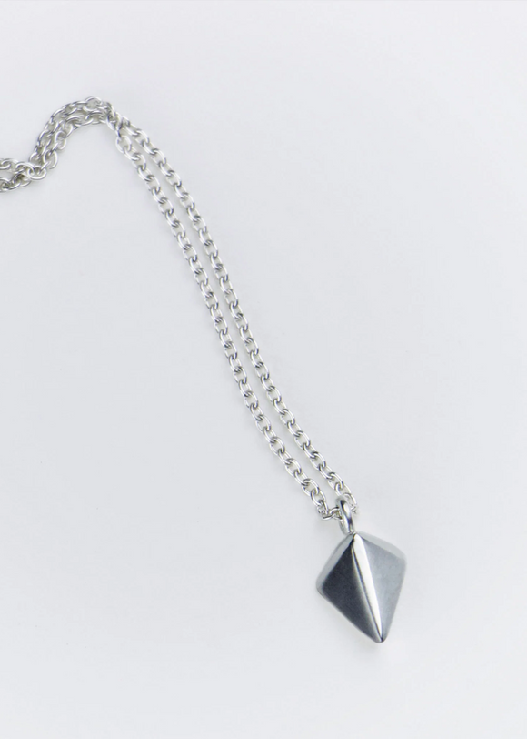 Silver necklace with a pyramid-shaped pendant on a light gray background