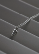 Silver necklace with a triangular pendant on a gray surface
