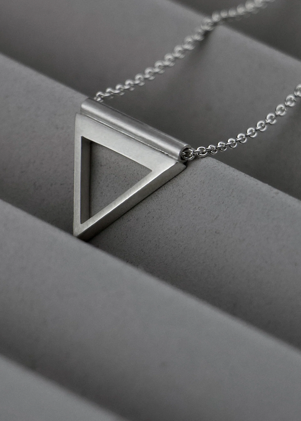 Silver triangle pendant necklace on a gray surface