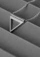 Silver triangle pendant necklace on a gray surface
