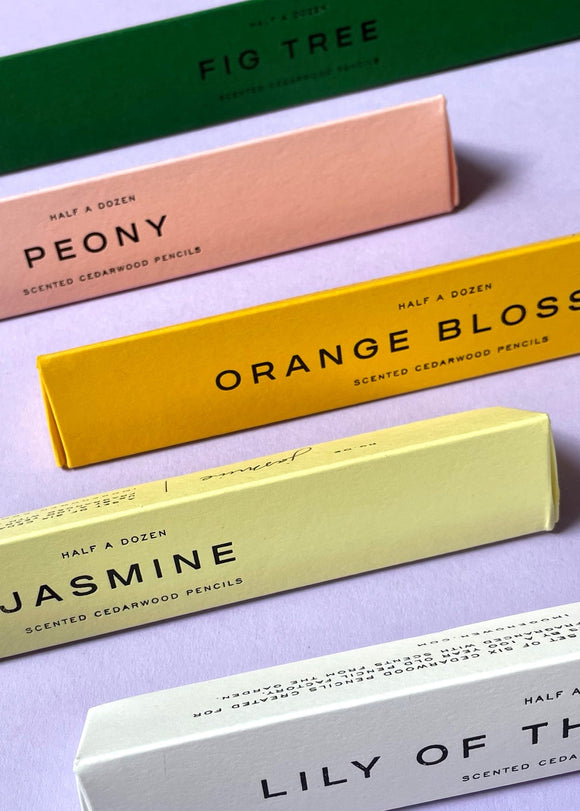 Colorful boxes of scented cedarwood pencils on a light purple background