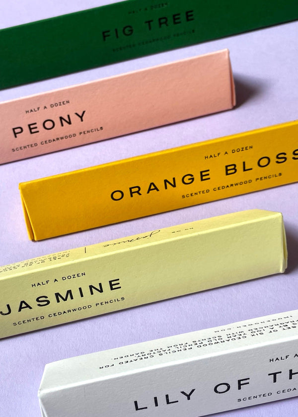 Colorful boxes of scented cedarwood pencils on a light purple background