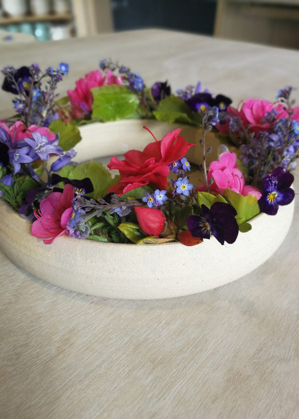 Floral wreath with colorful flowers on a wooden surface