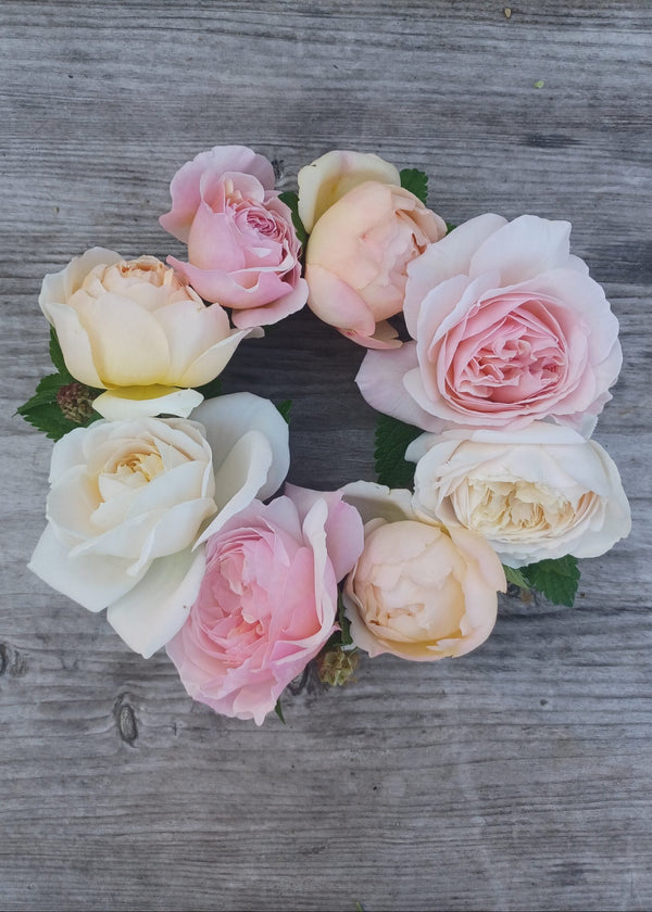 Floral wreath with pink, white, and yellow roses on a wooden surface