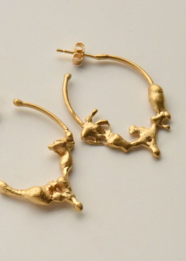 A pair of oval-shaped hoop earrings with a gold-colored bronze rock-like formation and silver hoops.