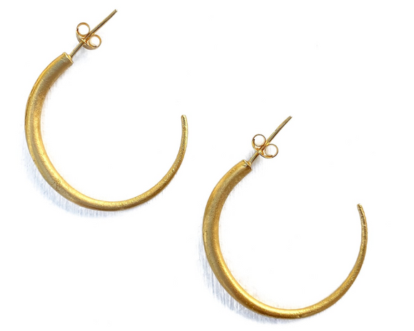 A pair of gold-colored oval tapered hoop earrings with a matte finish.