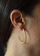 Close-up of a person wearing a gold hoop earring with a dark background