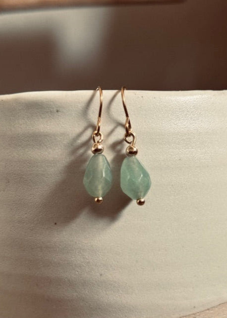 Teardrop-shaped green earrings on a light background
