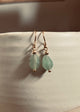 Teardrop-shaped green earrings on a light background