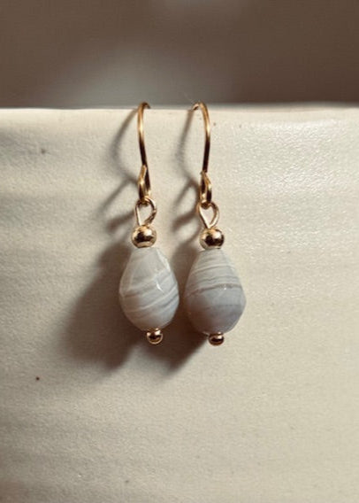 Teardrop-shaped earrings with gold accents on a light surface