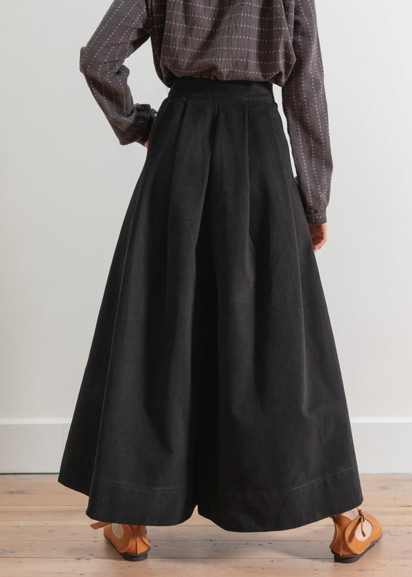 Person wearing a plaid shirt and black wide-leg pants on a plain background